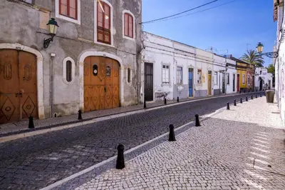 a cobblestone street in an old town with wooden doors at Faro Tradicional House - City center in Faro