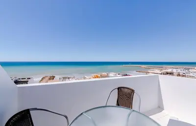 a view of the beach from a balcony with a table and chairs at Sky - wonderful view to the beach - Quarteira in Quarteira