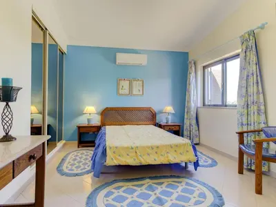 a bedroom with a bed and a blue wall at Casa Vilamoura in Vilamoura