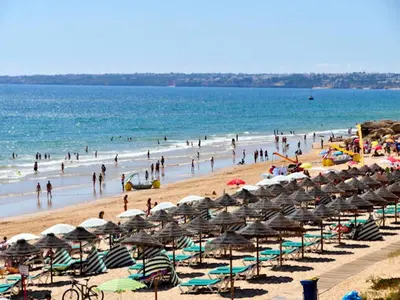 a beach with many umbrellas and people in the water at Beautiful Loule Villa Villa Quinta Tropical Private Pool Air Conditioning in Loulé