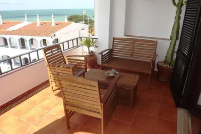 a balcony with chairs and a table and a view of the ocean at Casa Nill - Apartamento na Praia do Forte de São João em Albufeira in Albufeira