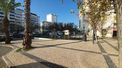 a sidewalk with trees and a playground in a city at Apartamento de Quarteira in Quarteira