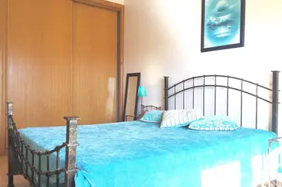 a bedroom with a bed with a blue comforter at Edificio Sao Joao das areias Strip l OURA in Albufeira