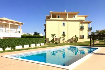 a villa with a swimming pool in front of a house at Edificio Sao Joao das areias Strip l OURA in Albufeira