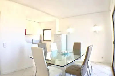 a dining room with a glass table and white chairs at Bellavista Avenida Pool and city center in Albufeira
