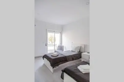 a white bedroom with a bed and a chair at REMODELED APARTMENT IN THE CITY CENTER. (FARO) in Faro