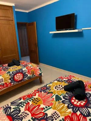a bedroom with two beds and a tv on the wall at OCEAN VIEW Quartos in Faro