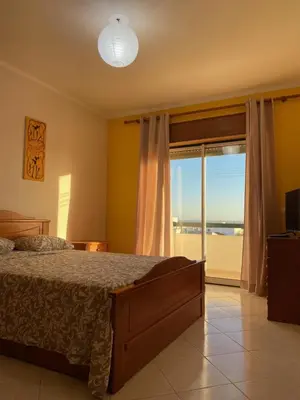 a bedroom with a bed and a large window at OCEAN VIEW Quartos in Faro