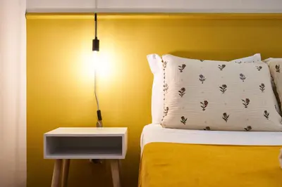 a bed with a white pillow and a nightstand with a lamp at Baron Faro - Guest House in Faro