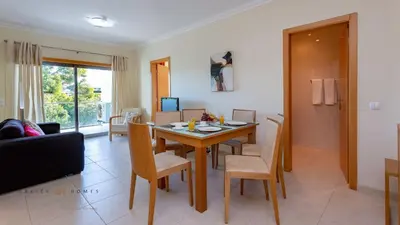 a living room with a dining room table and chairs at Greice Homes-Apartamento 2 quartos, Monte da Balaia, Olhos de Água, Albufeira in Olhos de Água