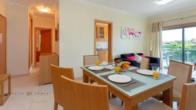 a dining room and living room with a table and chairs at Greice Homes-Apartamento 2 quartos, Monte da Balaia, Olhos de Água, Albufeira in Olhos de Água