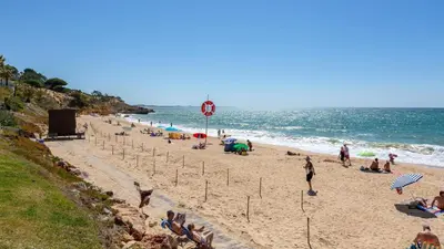 a beach with people sitting on the sand and the ocean at Greice Homes-Apartamento 2 quartos, Monte da Balaia, Olhos de Água, Albufeira in Olhos de Água