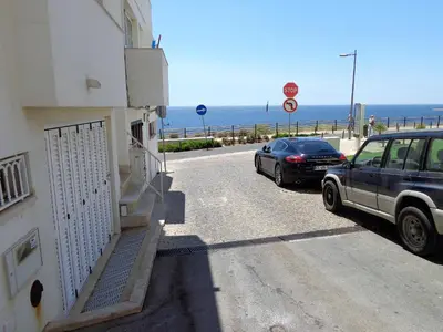 a car parked next to a building next to the ocean at Waves Studio - Albufeira in Albufeira
