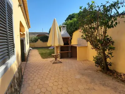 a patio with an umbrella and a table and an umbrella at Quinta Vita - Vila Pera in Almancil