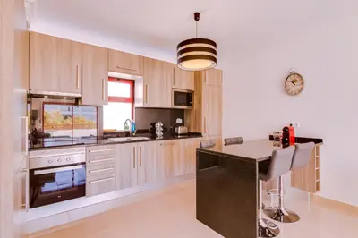 a kitchen with wooden cabinets and a black counter top at Varandas do Mar - Near the beach - Quarteira in Quarteira