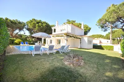 a villa with a swimming pool with chairs and an umbrella at Charming Villa, Private Pool, Walking Distance to Centre, Free AC Wifi in Quarteira