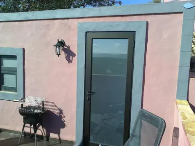 a pink and blue building with a door and a chair at Casa Do Forno - Quinta Amoreira in Faro