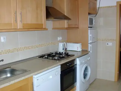 a kitchen with a stove top oven next to a washing machine at Albufeira 1 bedroom apartment 5 min from Falesia beach and close to center J in Albufeira