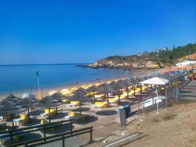 a beach with umbrellas and people on the water at Villa 81 great spot Oura beach, Albufeira in Albufeira
