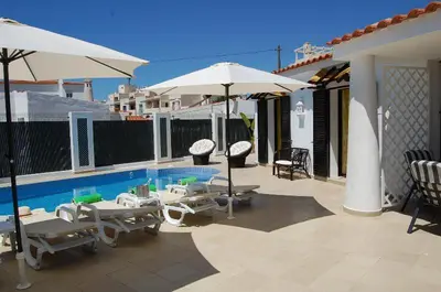 a patio with chairs and umbrellas and a swimming pool at Villa 2, great spot Oura beach, Albufeira in Albufeira