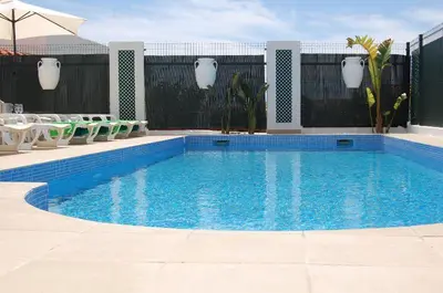 a large blue swimming pool with chairs and a fence at Villa 2, great spot Oura beach, Albufeira in Albufeira