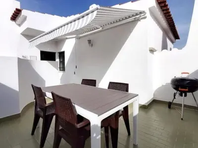 a white patio with a table and chairs and a grill at Areias Apartment by Stay ici Algarve Holiday Rental in Albufeira