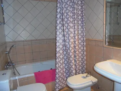 a bathroom with a toilet and a tub and a sink at Jardim Paraiso Apartments in Albufeira