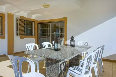 a dining room with a table and white chairs at Villa Machado in Albufeira