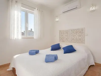 a white bedroom with a large white bed with blue pillows at Villa Villa Blue Ocean by Interhome in Patroves