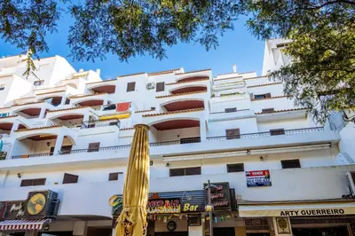 a large white building with a yellow umbrella in front of it at Top renoviertes Apartment mit großer Terrasse in Albufeira
