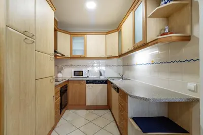 a kitchen with wooden cabinets and a counter top at Top renoviertes Apartment mit großer Terrasse in Albufeira