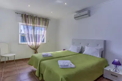 a bedroom with a green bed and a window at FLH Albufeira Vila Mira Flat with Pool in Albufeira