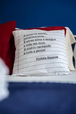 a pillow with writing on it sitting on a bed at Kwadalayo Art Quarters in Faro