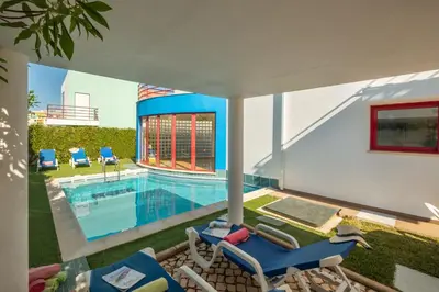a house with a swimming pool and two chairs at Villa Acapulco by Algarve Vacation in Albufeira