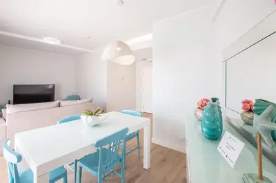a living room with a white table and blue chairs at Marina Design T1 in Albufeira