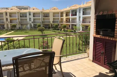 a balcony with a table and chairs and a building at Vila Columbus T2 Frente Mar e Piscina in Quarteira
