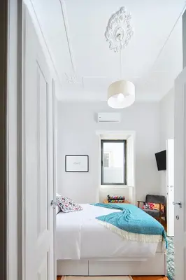 a bedroom with white walls and a bed with a blue blanket at Pereiras House of Charm - Downtown in Faro