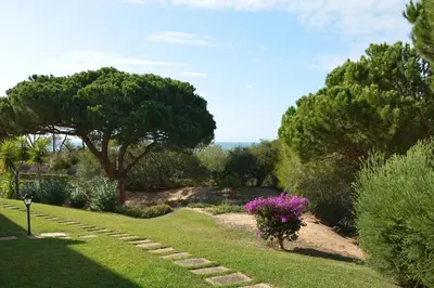 a garden with purple flowers and trees and a path at Paradise Beach Villa in Albufeira