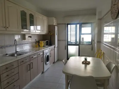 a kitchen with a table and a sink and a dishwasher at Penha House in Faro
