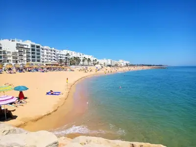 a beach with people and buildings and the ocean at Solaris- Familiar, Wifi, Totalmente Equipado in Quarteira