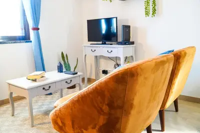 a living room with a chair and a tv and a table at Villa Marrachinho in Albufeira