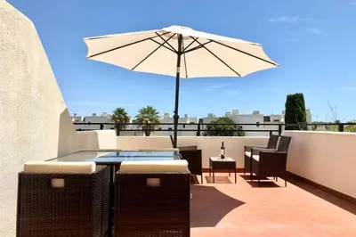 a table and chairs with an umbrella on a balcony at Albufeira Jardim l old town and beach - Hawai in Albufeira
