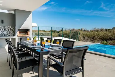a dining room with a table and chairs and a pool at Colinas do Golfe Vilamoura Sun by SAPvillas in Vilamoura