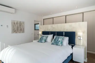 a bedroom with a large white bed with blue pillows at Colinas do Golfe Vilamoura Sun by SAPvillas in Vilamoura