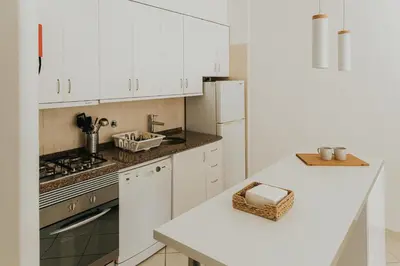 a kitchen with white cabinets and a white counter top at Soleil Apartment in Quarteira