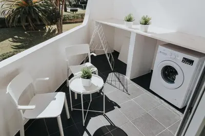 a laundry room with a washing machine and chairs at Soleil Apartment in Quarteira