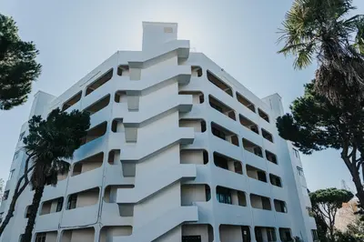 a white building with trees in front of it at Soleil Apartment in Quarteira