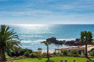 a view of a beach with palm trees and the ocean at Apartment Aveiros Beach- D´Alma Amado in Albufeira