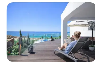 a pool with chairs and a beach in the background at Villa Front de Mer avec Piscine Jacuzzi Accès Privé Plage en famille et entre amis in Albufeira