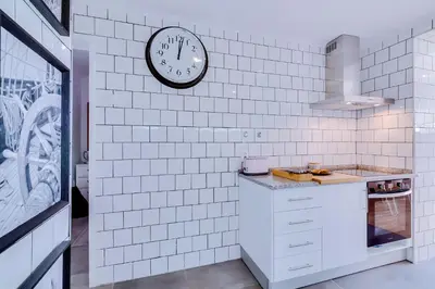 a white kitchen with a clock on the wall at Groundfloor in Faro